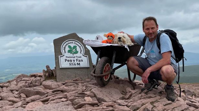 A man pushes his dog on a wheelbarrow's crest at the end of his life: 
