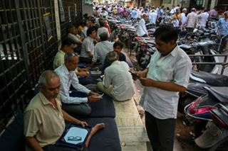 Des vendeurs assis devant le marché aux diamants à Surate, dans l'Etat de Gujarat, la ville du diamant. Photo prise le 31 mai 2022